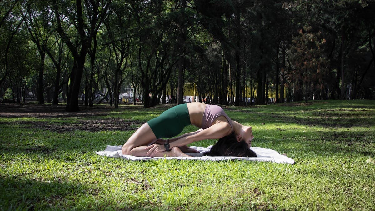 Woman performing a yoga pose on a sunny day in a lush green park in Ciudad de México.